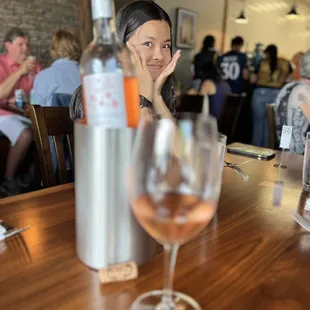 a woman sitting at a table with a glass of wine