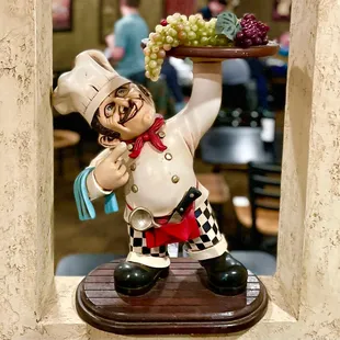 a statue of a chef holding a tray of grapes