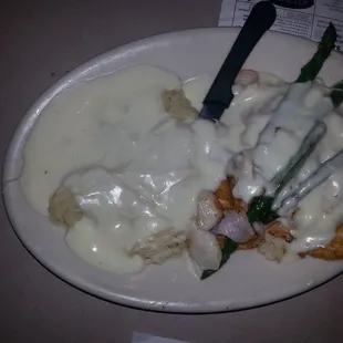 The crabby chicken is a saucy derivative of Chicken Oscar topped with Alfredo sauce and garnished with asparagus.