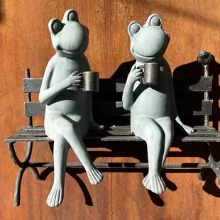 two frogs sitting on a bench