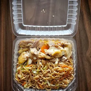 a take out container with noodles and meat