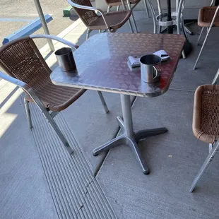 empty tables and chairs on a sidewalk
