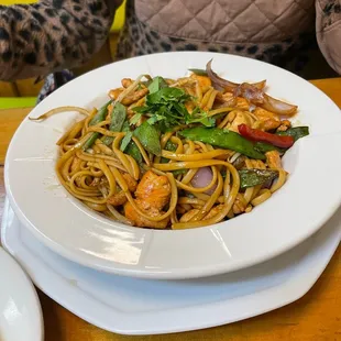 a plate of noodles with shrimp and vegetables