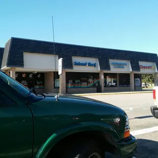 a green truck parked in front of a store