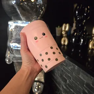 a hand holding a pink boba cup
