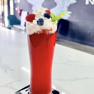 a red drink with whipped cream and berries