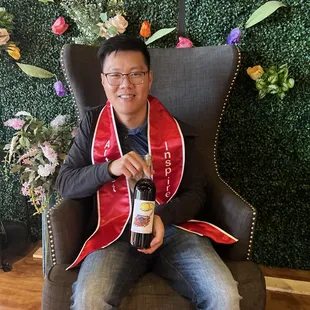 a man sitting in a chair holding a bottle of wine