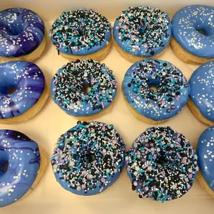 a box of blue frosted donuts with sprinkles