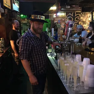 a man standing at a bar with glasses of champagne