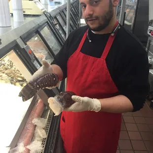 a man in a red apron holding a donut