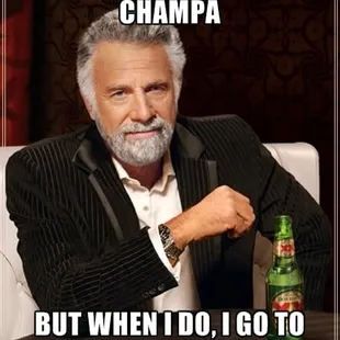 a man in a suit sitting at a table with a bottle of beer