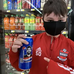 a man in a face mask holding a can of soda