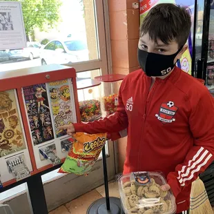 a boy wearing a face mask and holding a bag of cookies