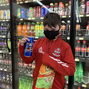 a man in a face mask holding a can of soda