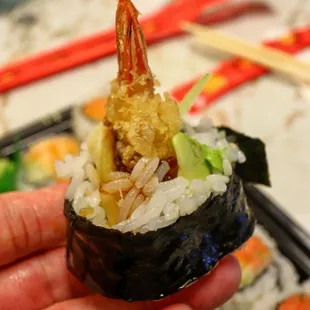 a hand holding a piece of sushi
