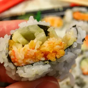 a hand holding a piece of sushi