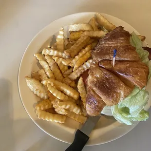 Chicken Croissant bacon avocado sandwich with fries.