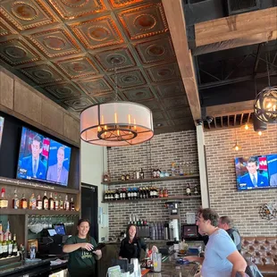 people sitting at a bar watching tvs