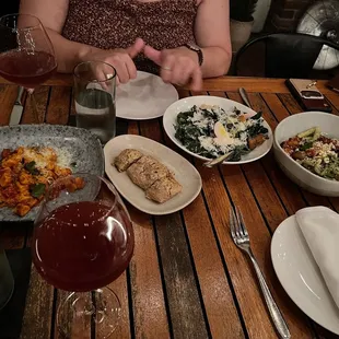 a woman sitting at a table with food and wine