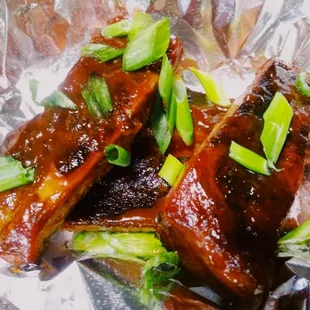 a close up of ribs with green onions