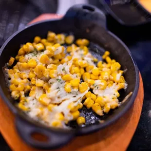 a skillet filled with corn and cheese