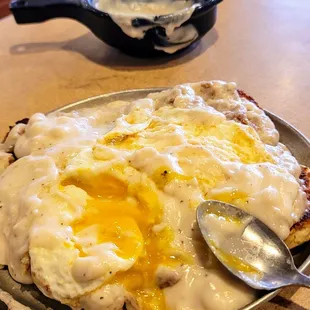 Southern tradition: Two giant grilled biscuits fresh pipin hot, sausage gravy two eggs over medium on top