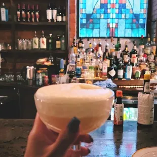 a hand holding a glass of cocktail