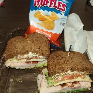 Turkey Club sandwich on Squaw bread with chips and pickle.