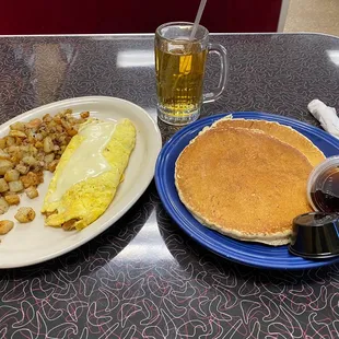 Steak omelette, home fries, apple juice and two pancakes