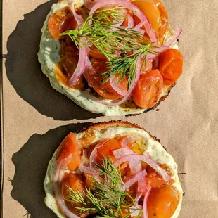 two bagels topped with tomatoes and onions