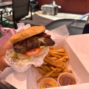 a hand holding a hamburger and fries