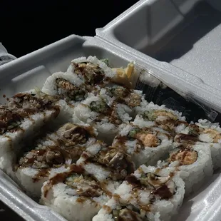 a close up of sushi in a styrofoam container