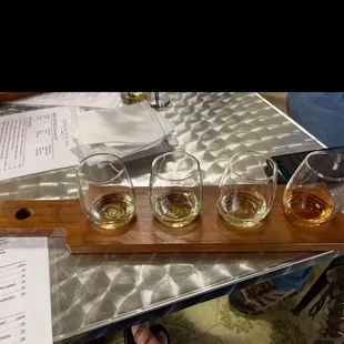 four glasses of wine on a wooden tray