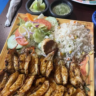  a plate of grilled shrimp and rice with a side salad