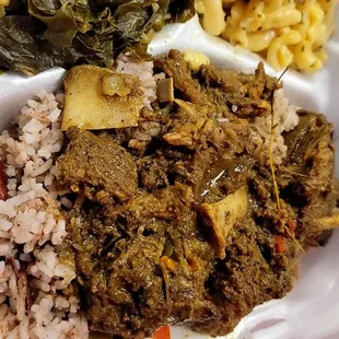 Curry goat with rice and peas - greens and mac and cheese as sides