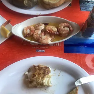 Grilled cod and garlic  prawns with baked potatoes  and bread .