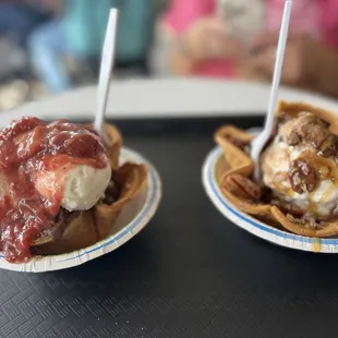 two waffle cones with ice cream and caramel sauce