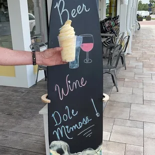 a person holding a surfboard with a drink on it