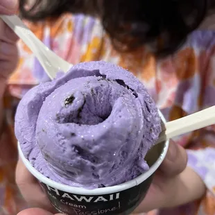 a woman holding a cup of purple ice cream