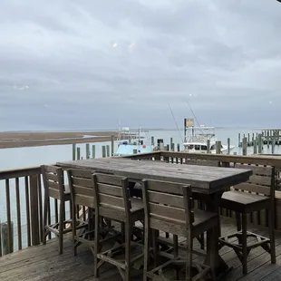 a table and chairs on a deck overlooking the water