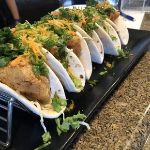 three fish tacos on a black plate