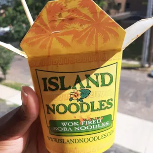 a hand holding a container of noodles