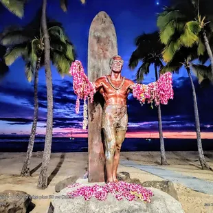 Sunset in Waikīkī @ 75°F. The Duke Paoa Kahinu Mokoe Hulikohala Kahanamoku statue. 1912 Olympic Gold medalist, Hawai'i surfing legend.