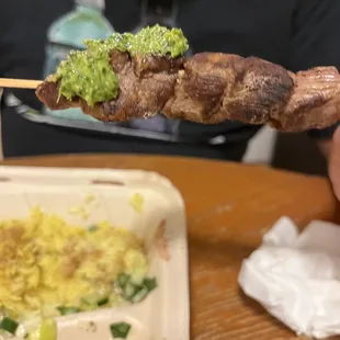 a person holding a skewer of food
