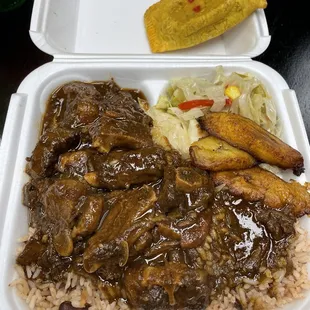 Oxtails, rice and peas, cabbage, fried plantains and a chicken curry patty