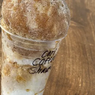 a cup of iced coffee with a sugared donut on top