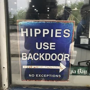 a sign in the window saying hippies use backdoor no exceptions