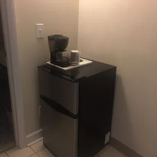 Microwave, coffee maker and decent sized refrigerator in the room.