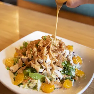 a plate of salad with dressing being drizzled over it