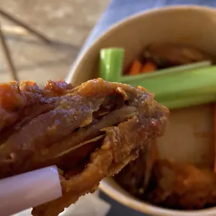 a hand holding a piece of fried chicken